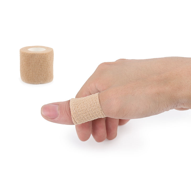 Beige elastisk bandagetape viklet om en tommelfinger med rulle ved siden af