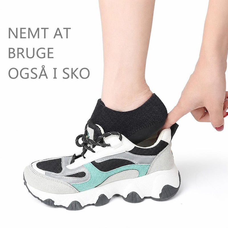 Sort hælskål på fod, der sættes ned i en sneaker