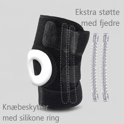 Sort knæstøtte med hvid silikonering og synlige fjedre ved siden af