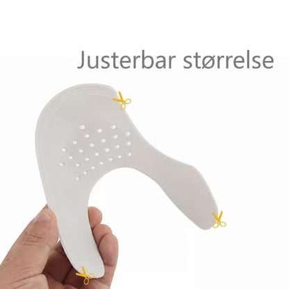 Hvid justerbar skobeskytter mod folder med perforeringer, holdt i hånden