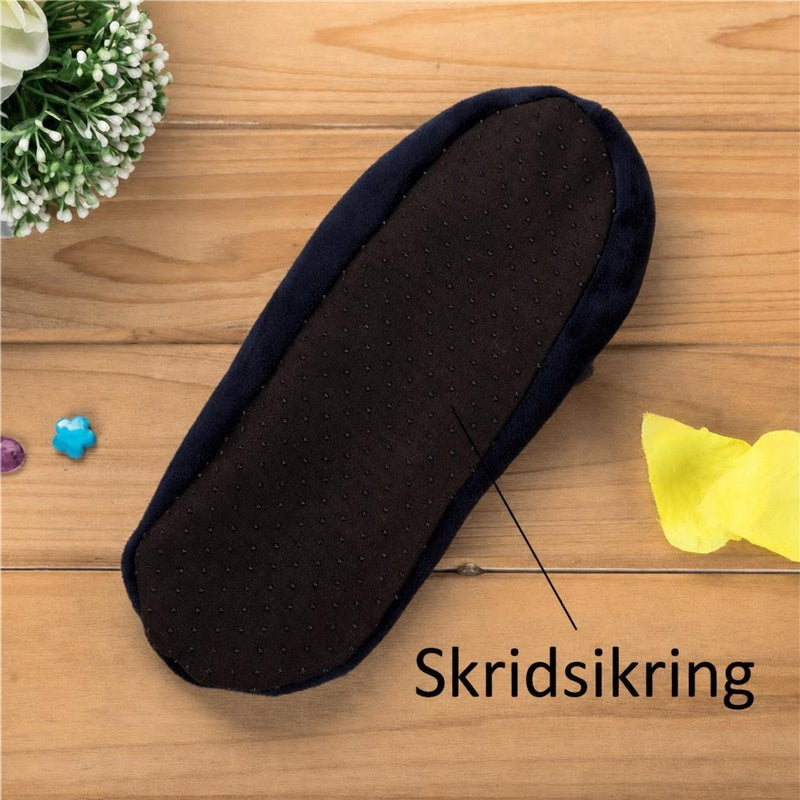 Sort hjemmesko med skridsikker sål på træbord