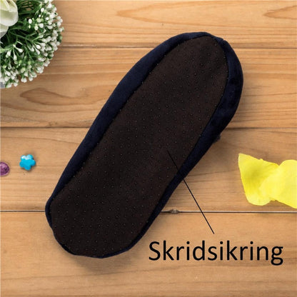 Blå hjemmesko med sort skridsikker sål på træbord