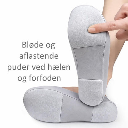 Grå lave strømper med polstrede såler, hvor en finger trykker på forfoden
