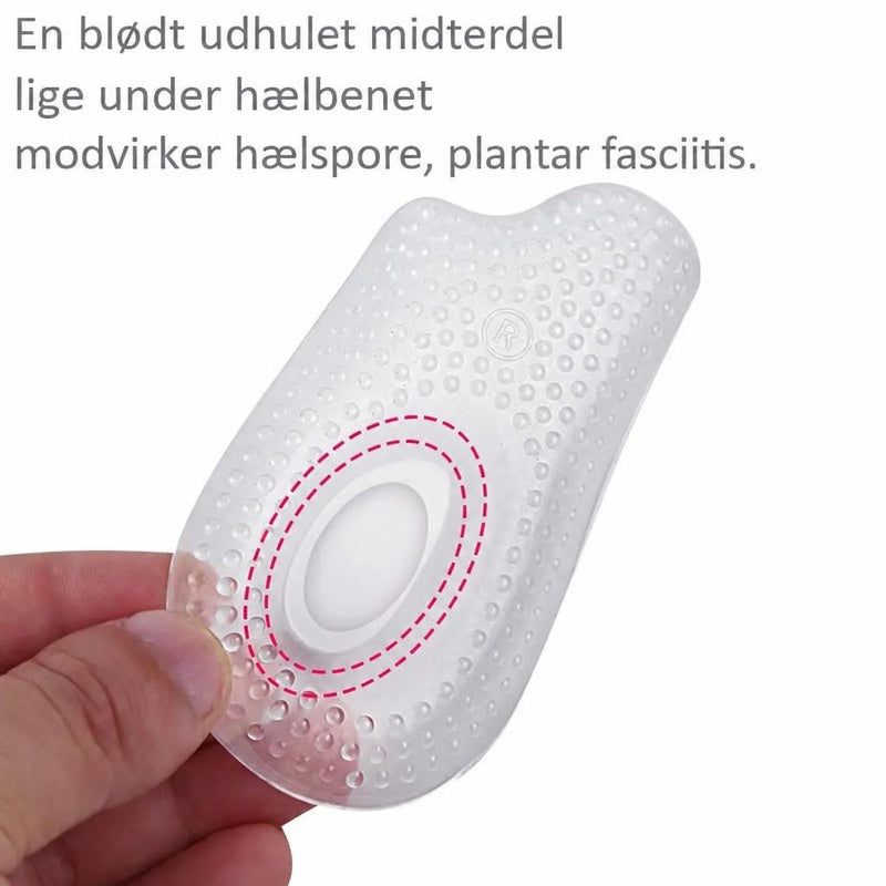 Gennemsigtigt gel-hælindlæg med nopret overflade og oval fordybning, holdt i hånden