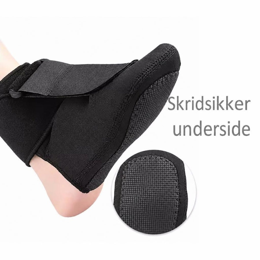 Sort natstrømpe med skridsikker underside på en fod