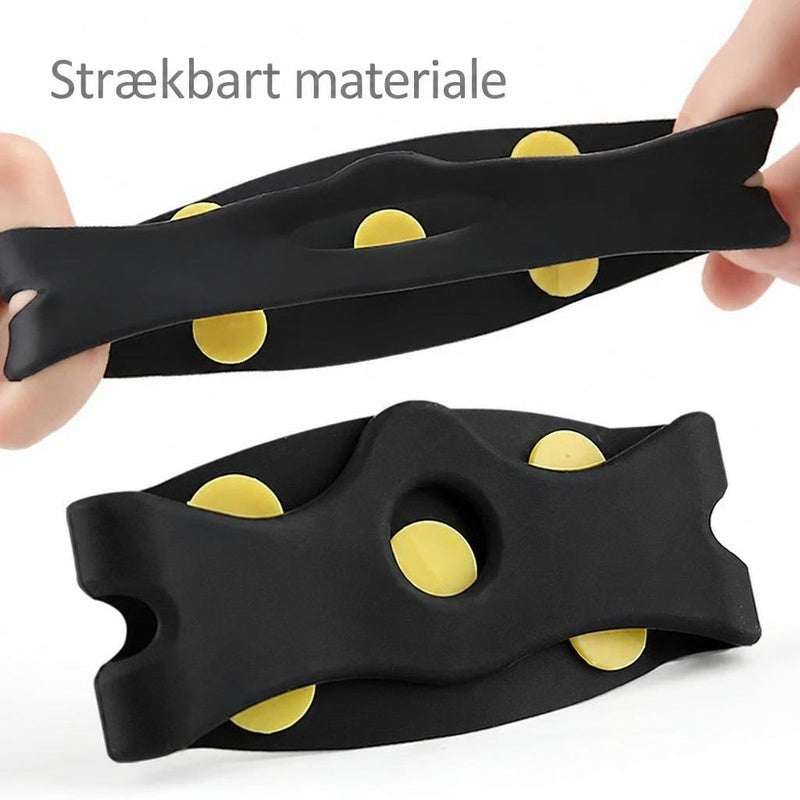 Sorte elastiske brodder med gule pigge, strakt mellem hænder
