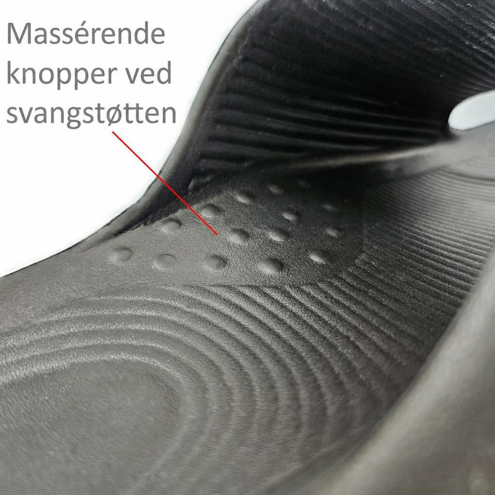 Sort tøffel med rillet indersål og knopper ved svangstøtten