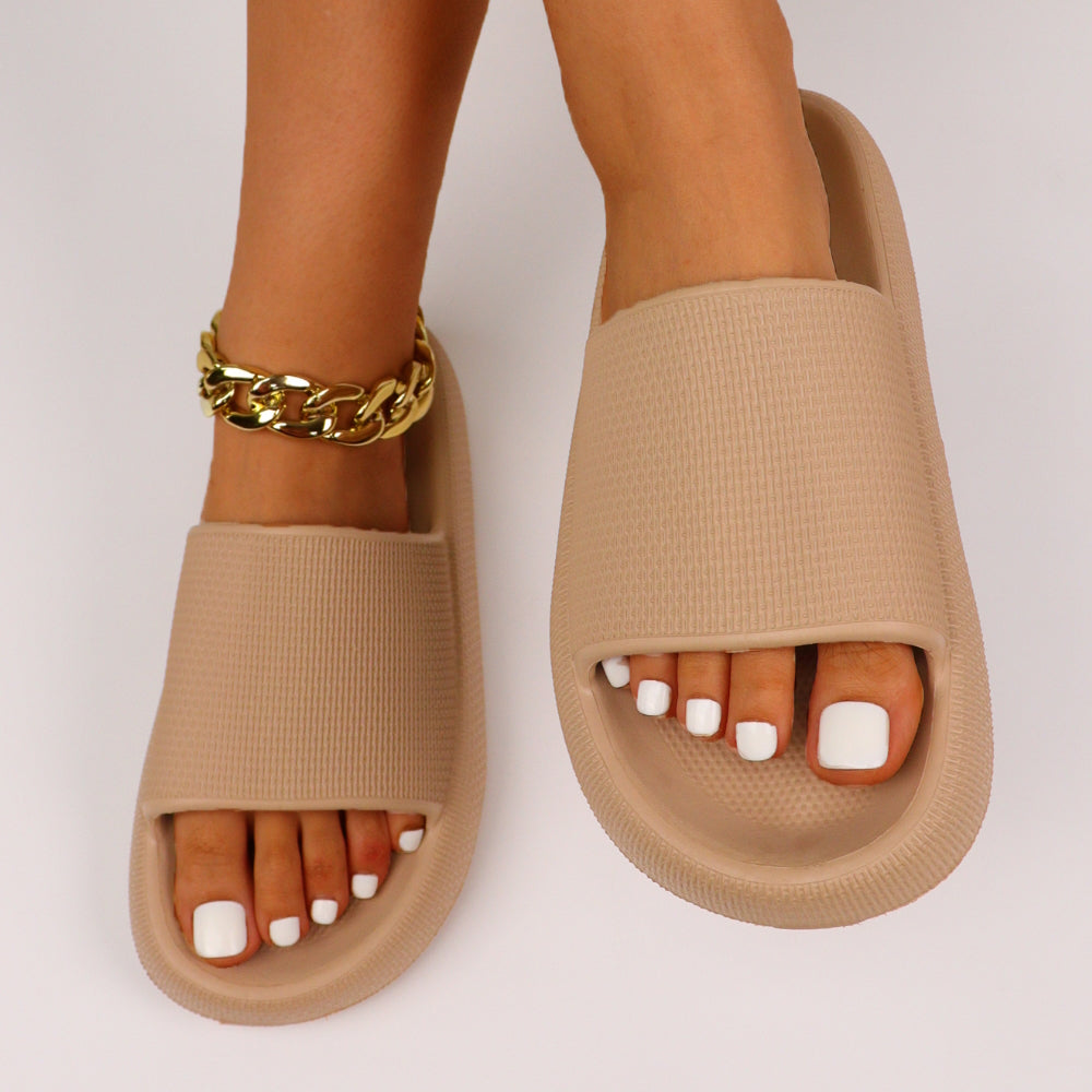 Beige slippers med bred rem, åben tå og guldfarvet ankelkæde