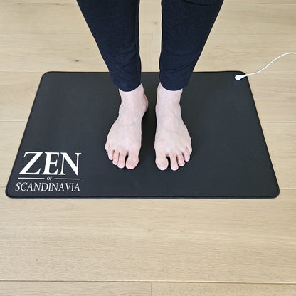 Bare fødder på sort jordingsmåtte med kabel og Zen Scandinavia-logo