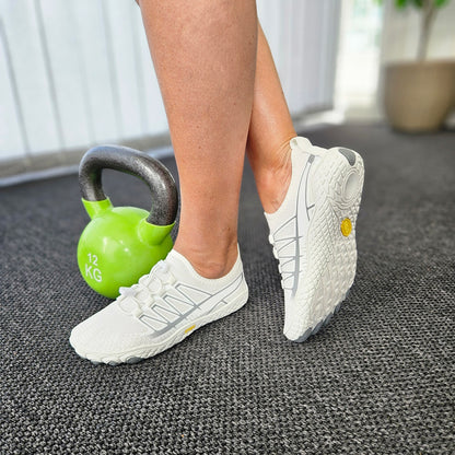 Hvide barfodssko på fødder ved siden af grøn kettlebell