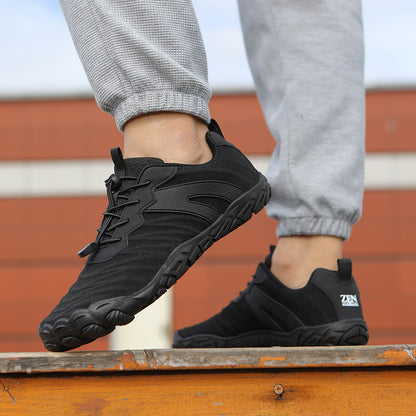 Sorte barfodssko med snørebånd på person i grå joggingbukser