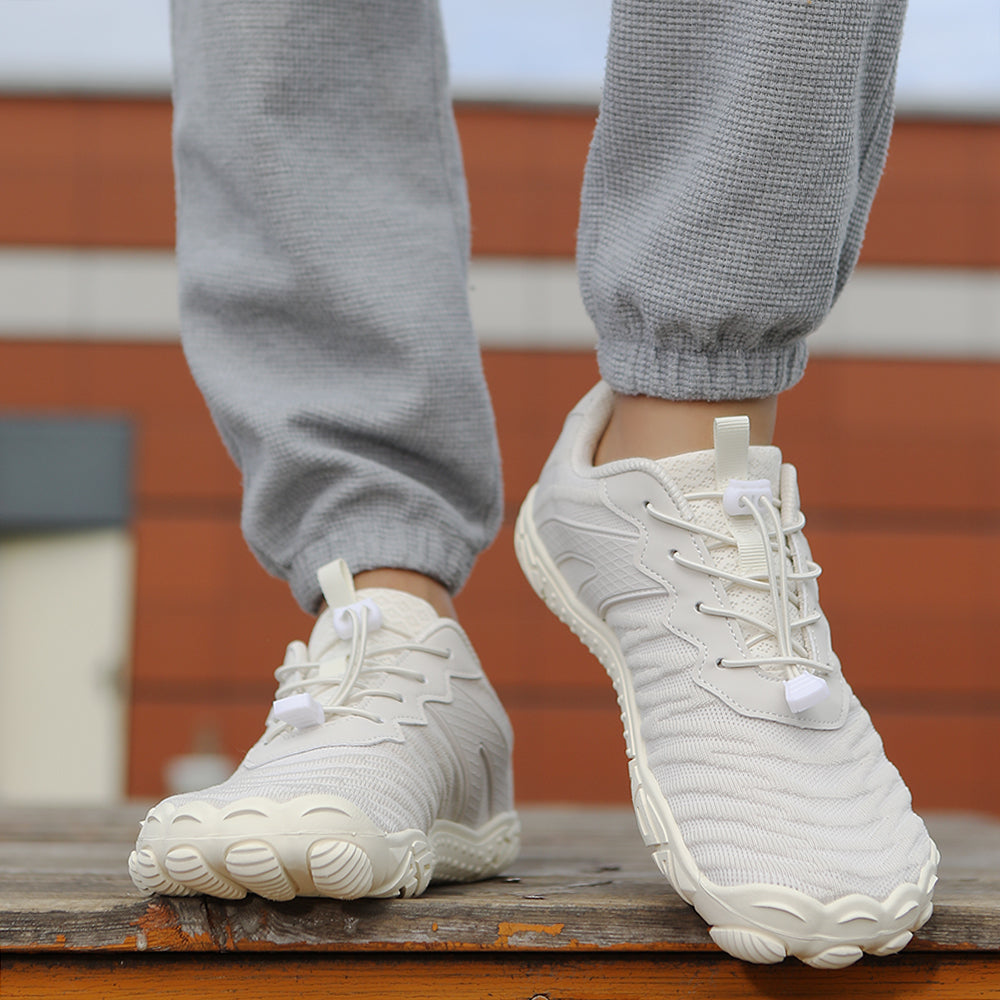 Hvide barfodssko med snørebånd på person i grå joggingbukser
