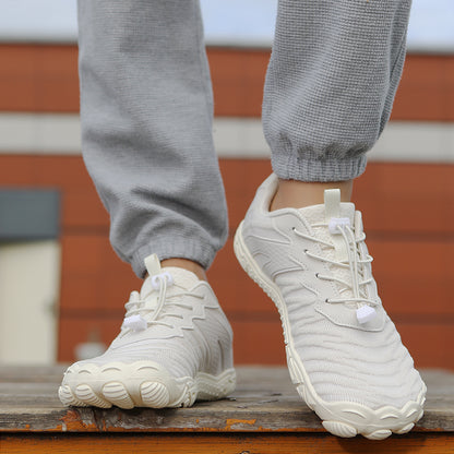 Hvide barfodssko med snørebånd på person i grå joggingbukser