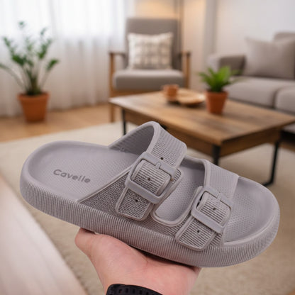 Grå justerbar tøffel med to spænder, holdt i hånden