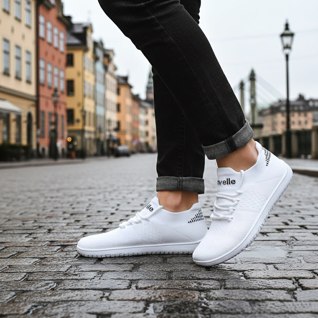 Hvide Ventra barfodssko på fødder med sorte opsmøgede jeans på brosten